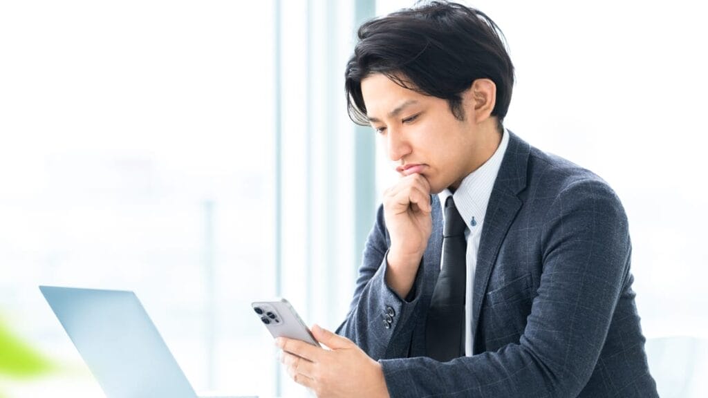 スマホを見て悩む男性