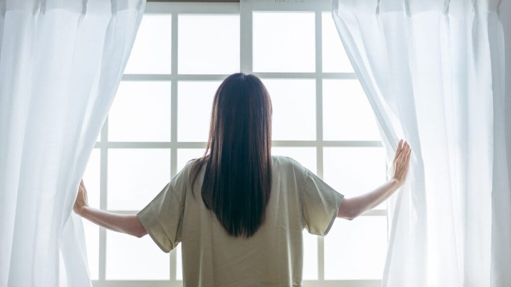 カーテンをあける女性